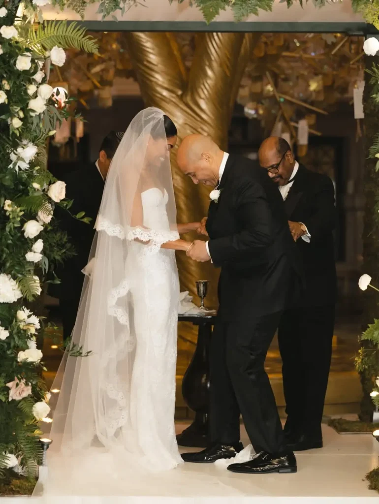 The newlyweds under the huppah, holding hands, both smiling like they won the lottery